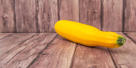 Yellow zucchini over wooden backgroundの写真素材
