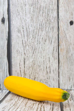 Yellow zucchini over wooden backgroundの写真素材