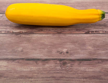 Yellow zucchini over wooden backgroundの写真素材