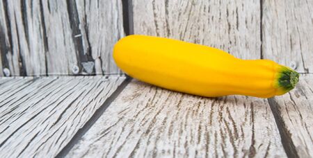 Yellow zucchini over wooden backgroundの写真素材