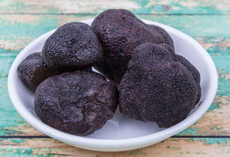 Black truffle mushroom in white bowl over wooden backgroundの写真素材
