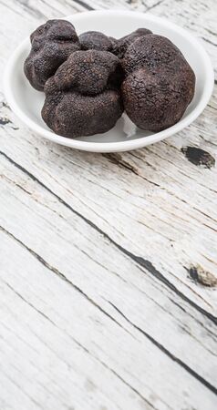 Black truffle mushroom in white bowl over wooden backgroundの写真素材