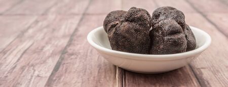 Black truffle mushroom in white bowl over wooden backgroundの写真素材