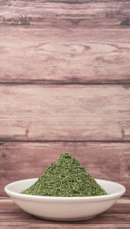Dried dill herbs in white bowl over rustic wooden backgroundの写真素材