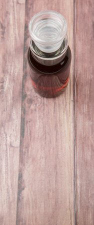 Maple vinegar in glass vial over wooden backgroundの写真素材