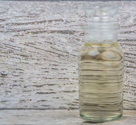 Apple vinegar in glass vial over wooden background