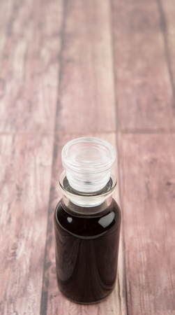 Italian balsamic vinegar in glass vial over wooden backgroundの写真素材