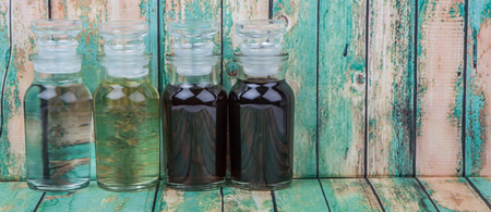 Vinegar, balsamic vinegar, maple vinegar and apple vinegar in glass vial over wooden background