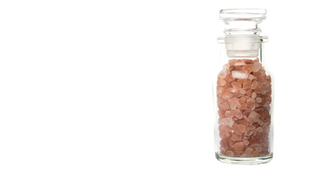 Himalaya or Himalayan rock salt in glass vial over white backgroundの写真素材