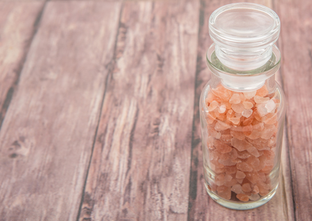 Himalaya or Himalayan rock salt in glass vial over wooden backgroundの写真素材