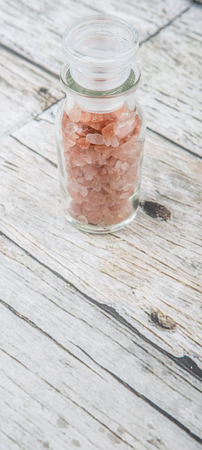 Himalaya or Himalayan rock salt in glass vial over wooden backgroundの写真素材