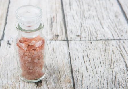 Himalaya or Himalayan rock salt in glass vial over wooden backgroundの写真素材
