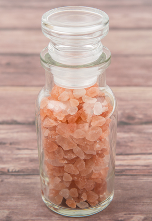 Himalaya or Himalayan rock salt in glass vial over wooden backgroundの写真素材