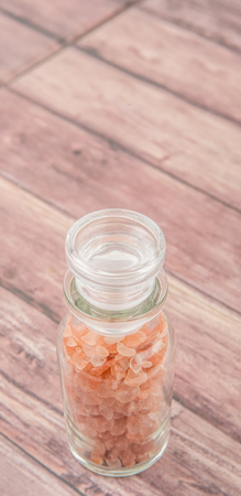 Himalaya or Himalayan rock salt in glass vial over wooden backgroundの写真素材