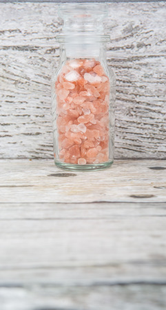 Himalaya or Himalayan rock salt in glass vial over wooden backgroundの写真素材