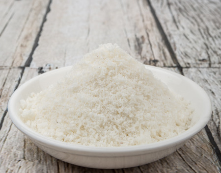 Dried coconut powder in white bowl over wooden backgroundの写真素材