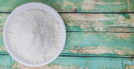 Dried coconut powder in white bowl over wooden backgroundの写真素材