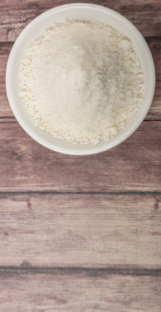 Dried coconut powder in white bowl over wooden backgroundの写真素材