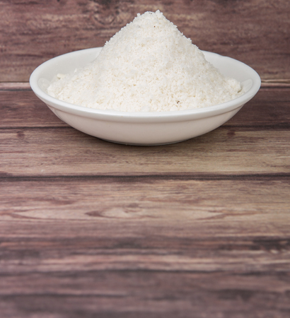 Dried coconut powder in white bowl over wooden backgroundの写真素材