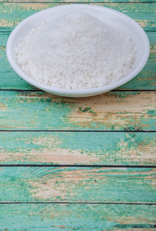 Dried coconut powder in white bowl over wooden backgroundの写真素材