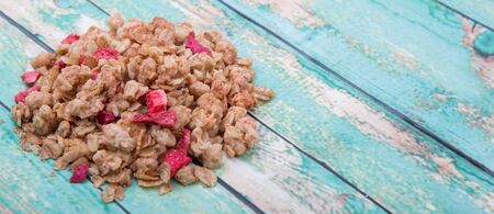 Breakfast cereal with dried raspberry fruit pieces over wooden backgroundの写真素材