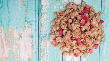Breakfast cereal with dried raspberry fruit pieces over wooden backgroundの写真素材