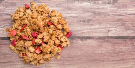 Breakfast cereal with dried raspberry fruit pieces over wooden backgroundの写真素材