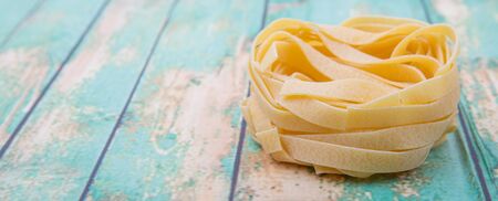 Dried tagliatelle pasta or ribbon shaped pasta or nest shape pasta over wooden backgroundの写真素材