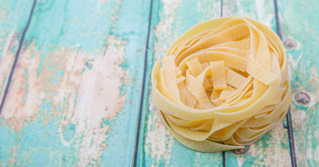 Dried tagliatelle pasta or ribbon shaped pasta or nest shape pasta over wooden backgroundの写真素材