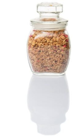 Breakfast cereal with dried raspberry fruit pieces in glass jar over white backgroundの写真素材