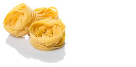 Dried tagliatelle pasta or ribbon shaped pasta or nest shape pasta over white backgroundの写真素材