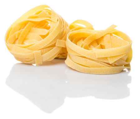 Dried tagliatelle pasta or ribbon shaped pasta or nest shape pasta over white backgroundの写真素材