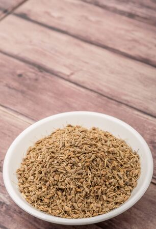 Dried anise seed or aniseed in white bowl over wooden backgroundの写真素材