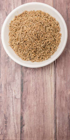 Dried anise seed or aniseed in white bowl over wooden backgroundの写真素材