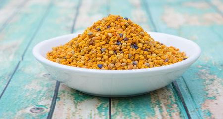 Bee pollen in white bowl over wooden backgroundの写真素材