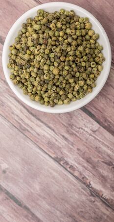 Dried green peppercorn in white bowl over wooden backgroundの写真素材