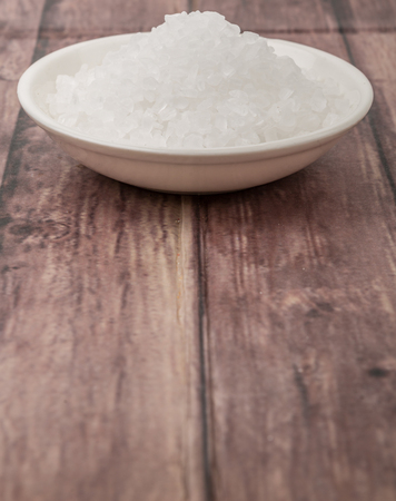 Sea salt in wooden bowl over wooden backgroundの写真素材
