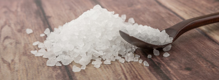 Sea salt on wooden spoon over wooden background