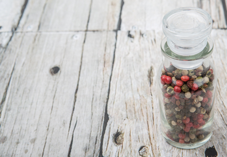 Mix peppercorn variety in vial glass over wooden background