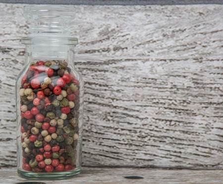 Mix peppercorn variety in vial glass over wooden backgroundの写真素材