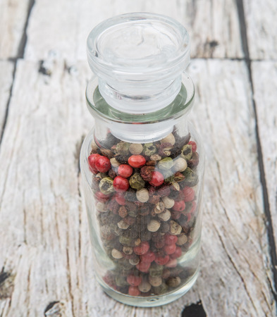 Mix peppercorn variety in vial glass over wooden backgroundの写真素材