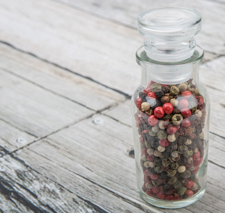 Mix peppercorn variety in vial glass over wooden backgroundの写真素材