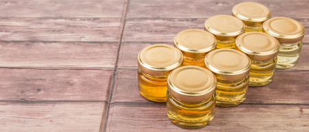 Different grade and color of honey in mason jar over wooden backgroundの写真素材