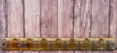 Different grade and color of honey in mason jar over wooden backgroundの写真素材