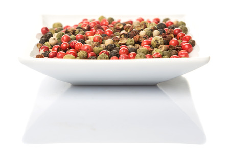 Mix peppercorn variety in square bowl over white background