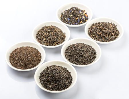 Dried variety of black tea leaves in white bowl over white backgroundの写真素材