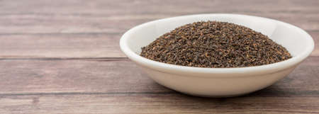 Black Ceylon tea in white bowl over wooden backgroundの写真素材