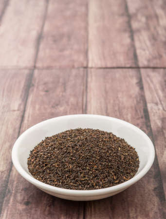 Black Ceylon tea in white bowl over wooden backgroundの写真素材