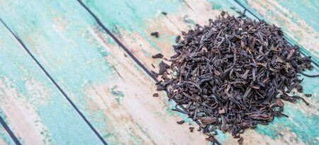 Loose dried darjeeling black tea leaves over wooden background