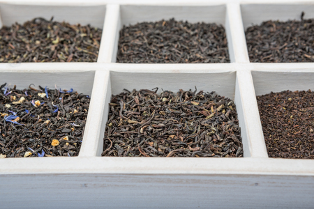 Dried variety of black tea leaves in white square box over wooden backgroundの写真素材
